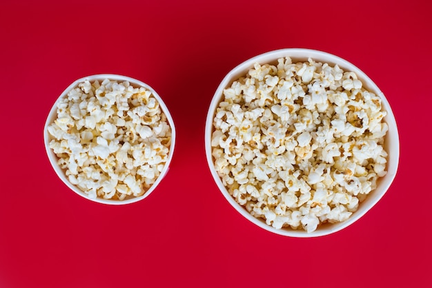 Top view photo of two boxes with popcorn isolated red background