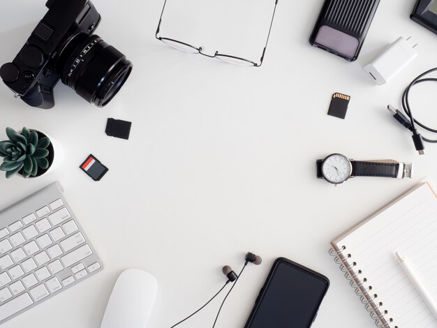 Photo top view of photographer work station, work space concept with digital camera, memory card, keyboard and smartphone on white table background