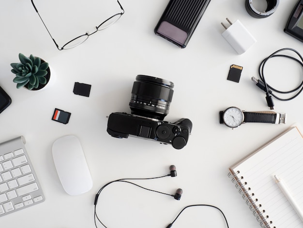 top view of photographer work station, work space concept with digital camera, memory card, keyboard and smartphone on white table background