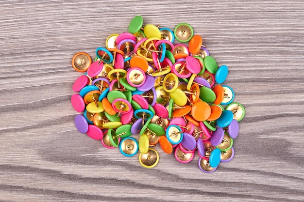 Top view pile of push pins on white wooden desk