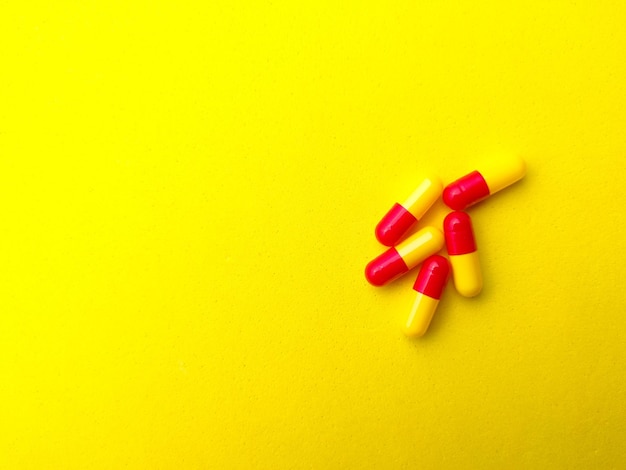 Top view piles of pills and capsules with copy space on yellow\
backgroundselective focus