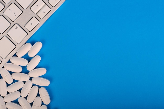 Top view pills near keyboard on blue Medical background