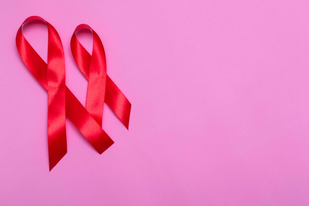 Top view on pink background with red ribbon concept December 1st International AIDS Day close-up.