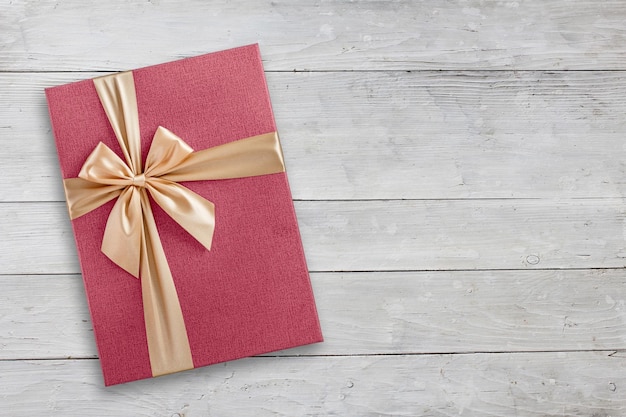 Top view of pink gift box with golden ribbon on wooden background copy space