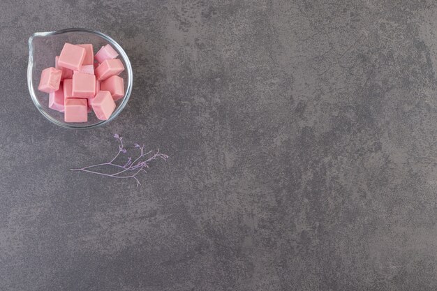 Top view of pink gums in glass bowl over grey surface