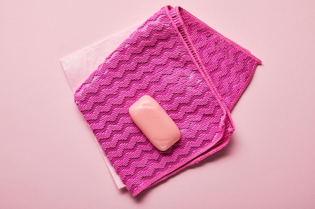 Top view of pink rags and soap on pink background