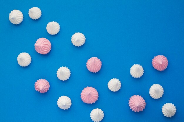 Photo top view of pink and white meringue on the blue background copy space