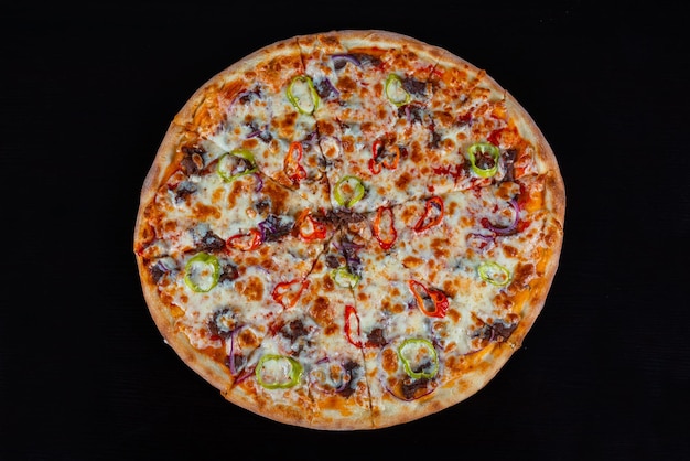 Top view of pizza with meat and vegetables on a black background