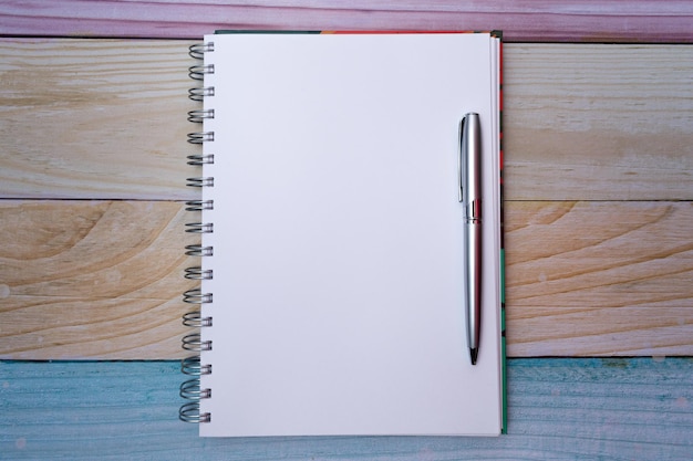Top view of a plain white sheet notepad and a pen, on a background of colored madras