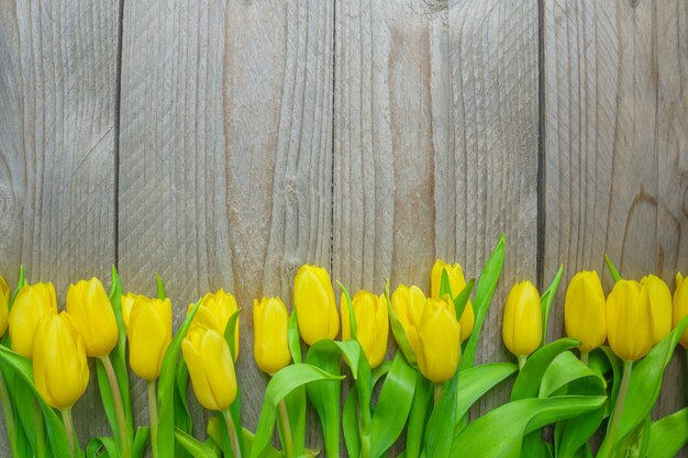 Photo top view of planty yellow tulips on wooden background. concept of women and mother day. festive greeting card.