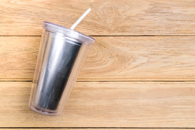 Top view plastic tumbler cup with straw or tube on wooden background