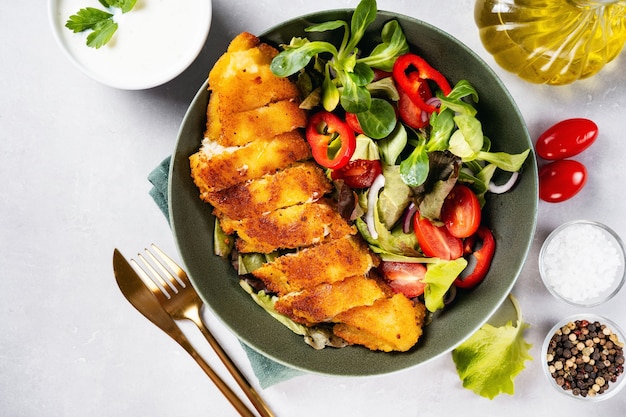 Top view of a plate with delicious breaded codfish with healthy salad