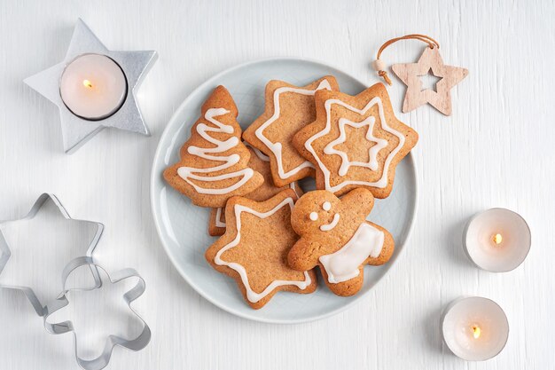 自家製の甘いジンジャーブレッド クッキーとプレートの平面図は、キャンドルと白い木製のテーブルで提供しています