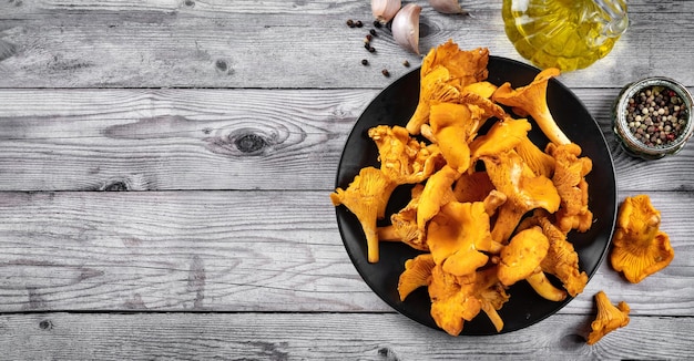 Top view on a plate with mushrooms chanterelles on gray woonden rustic background Lon banner Copy space