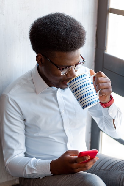  Top view of a pleasant young man drinking tea while resting from work