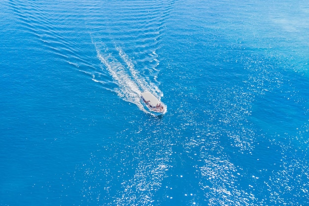 Top view of a pleasure boat with people floating on the blue sea