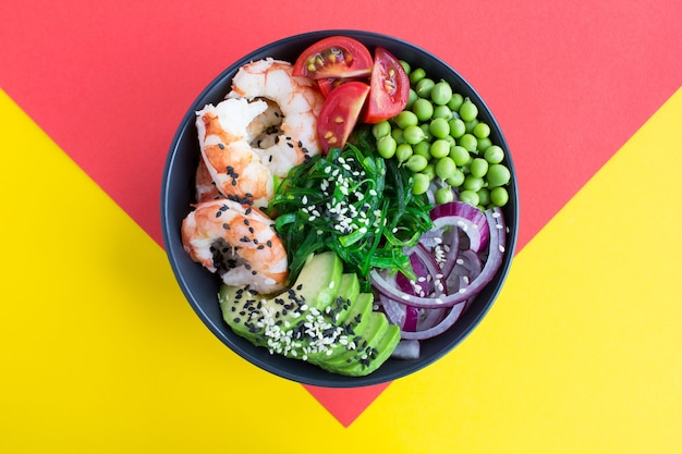 Top view of poke bowl with red shrimps and vegetables