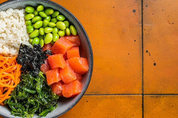 Top view of Poke bowl with Salmon Edamame and Rice Orange background Top view Copy space