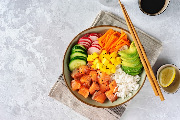 Top view of poke bowl with vegetables, rice and salmon