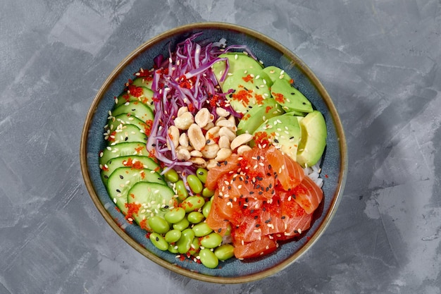 Photo top view on poke salad with salmon and green vegetable in the bowls on gray background copy space