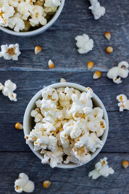 Top view of popcorn in a white bowl with a blue with popcorn.