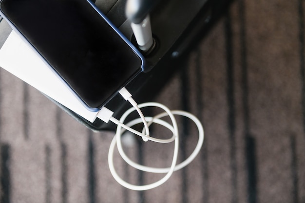 Top view of portable charging device for recharge mobile battery on travel suitcase in airport lounge