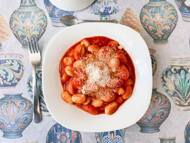 Photo top view of a portion of gnocchi in tomato sauce with grated parmesan cheese