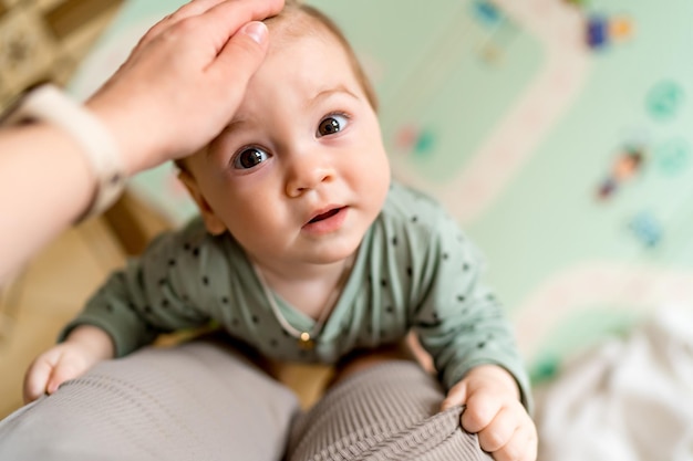 Top view of portrait of a baby boy embracing mothers leg A 9 month old baby lifting up on the leg