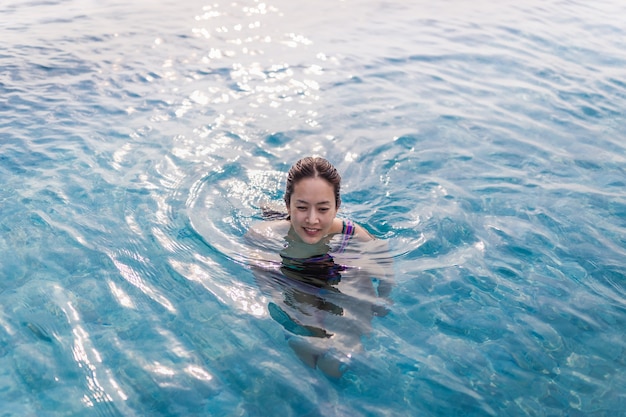 Top view of portrait of a smiling woman in swimming pool with wet hair.