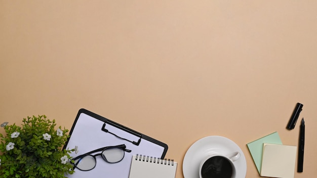 Top view potted plant clipboard and coffee cup on beige background