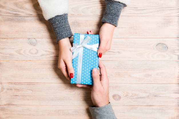 Vista dall'alto di un regalo in mani maschili e femminili