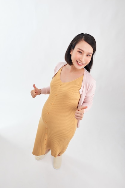 상위 뷰 꽤 웃는 임신 숙 녀 흰 벽 위에 절연 포즈