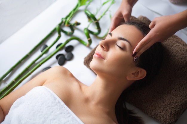 Top view of pretty woman laying in spa salon with closed eyes and relaxed