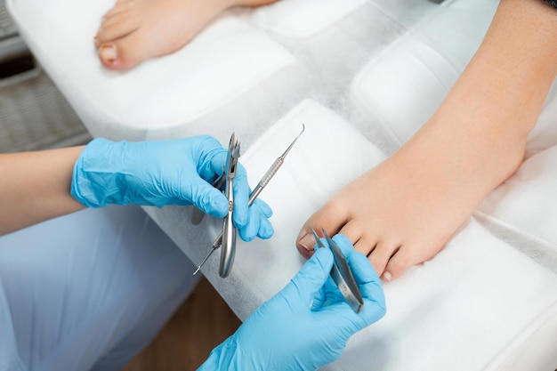 Top view of professional medical pedicure using special nail instruments in the clinic by podologist