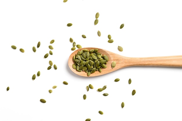 Vista dall'alto dei semi di zucca in cucchiaio di legno isolato su sfondo bianco serpente vegetariano o vegano alimentazione sana