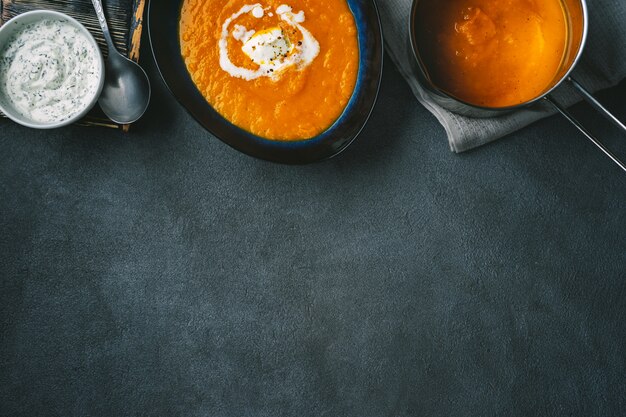 Top view of pumpkin soup in a plate and pot