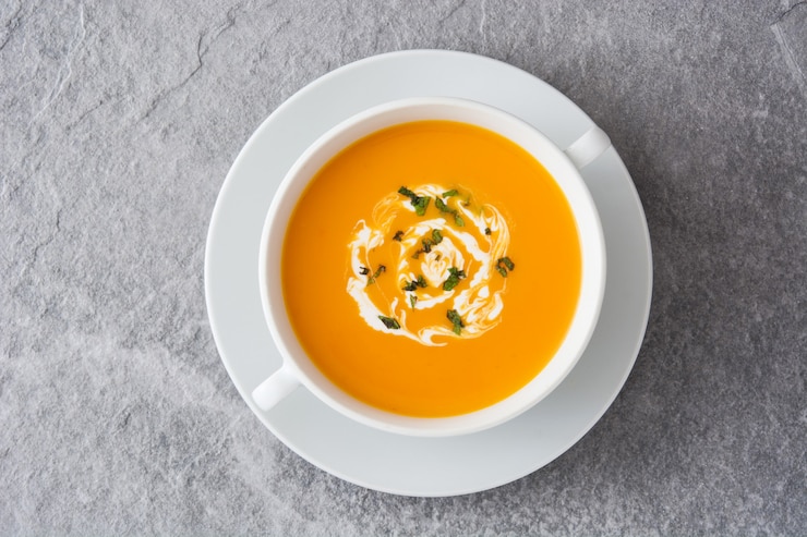 Photo top view on pumpkin soup in white bowl