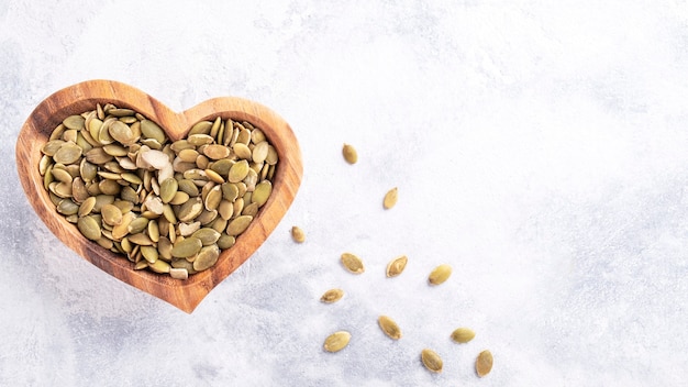 Top view of pumpkin sunflower seeds in a wooden bowl. Copy space