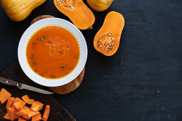 Top view of pureed pumpkin soup in a white bowl on dark table