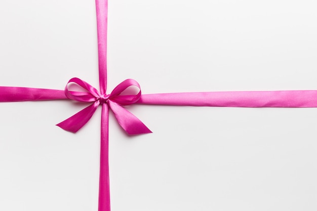 Top view of purple ribbon rolled and pink bow isolated on colored background Flat lay with copy space