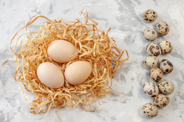 top view quail eggs and chicken eggs on straw on table