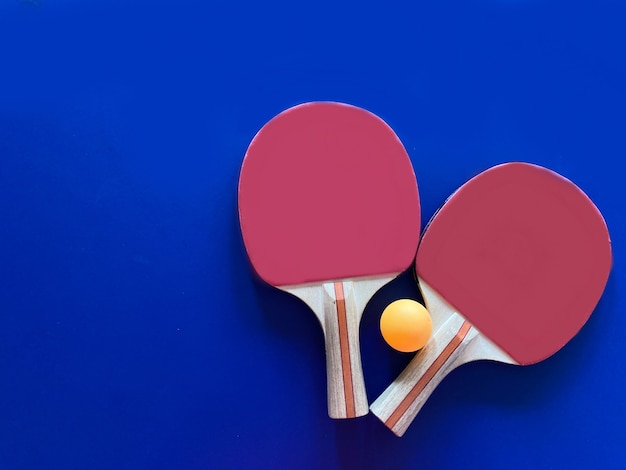 Top view of racket and table tennis ball on blue