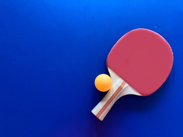 Top view of racket and table tennis ball on blue