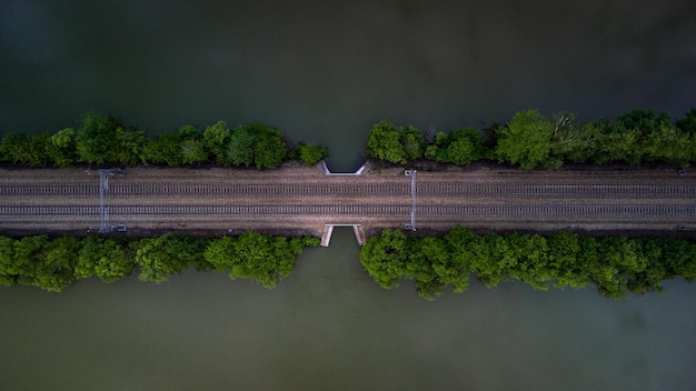 Top view of a railway line with trees running across a river