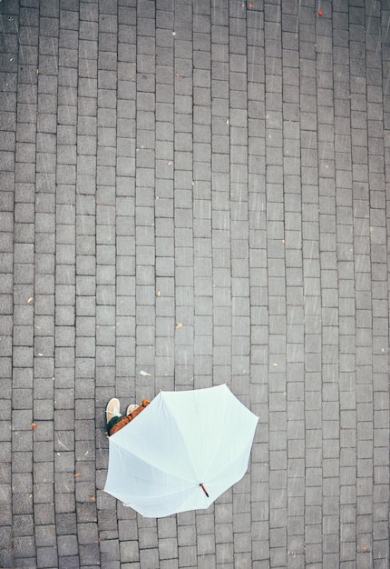 Photo top view rain and person with umbrella in city street or urban road mock up travel freedom and pedestrian with parasol on asphalt in winter weather traveling standing or enjoying time outdoors