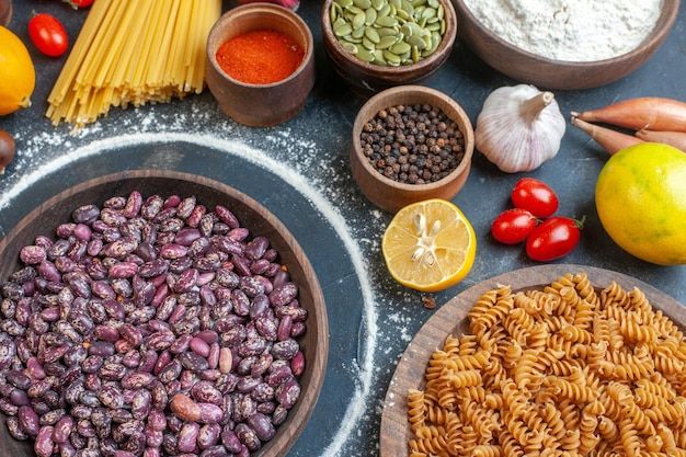 Top view raw beans with eggs nuts vegetables raw pasta and seasonings on dark background meal photo diet raw cake dish kitchen color