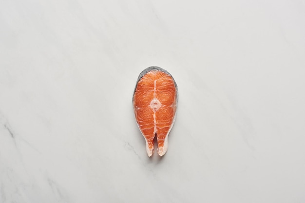 Top view of raw fresh salmon steak on white marble surface