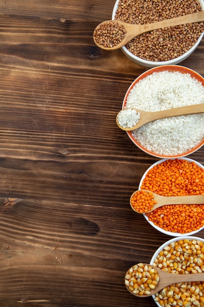 top view raw groats rice lentils corns and buckwheat in plates