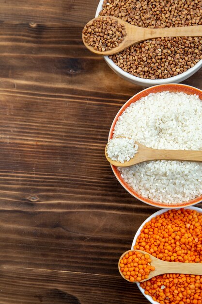 top view raw groats rice lentils corns and buckwheat in plates