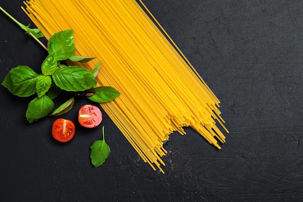 Top view of raw Italian pasta, tomatoes and basil